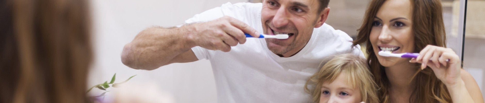 una familia cepillándose los dientes frente al espejo