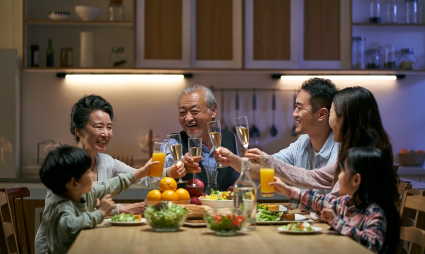 An Asian family of six toasting at the dinner table