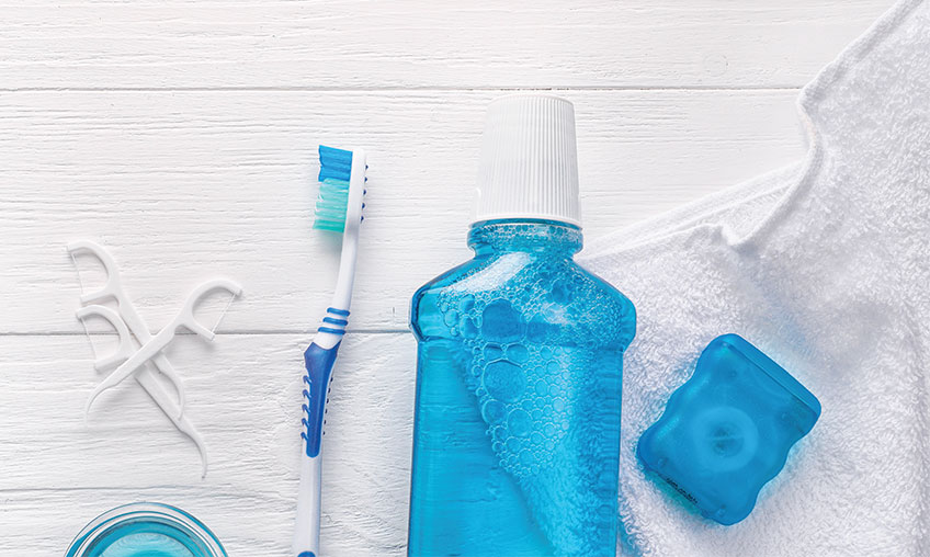 Toothbrush, toothpaste, mouthwash and floss on the bathroom counter