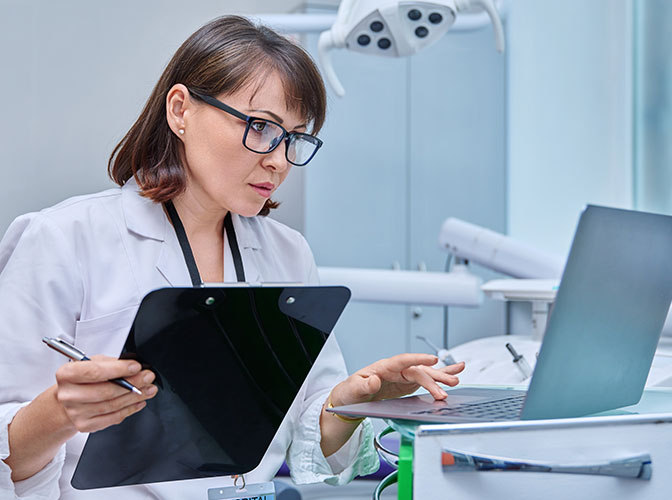 female dentist referencing computer