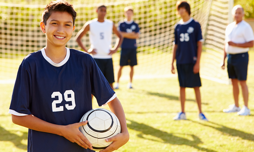 boy in foreground with soccer team and coach in background