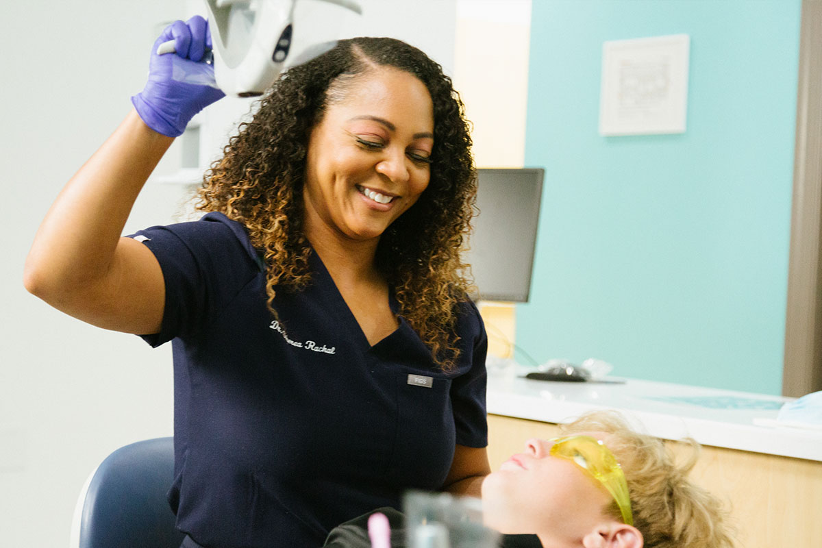 Dentista afroestadounidense examinando a un niño en su consultorio